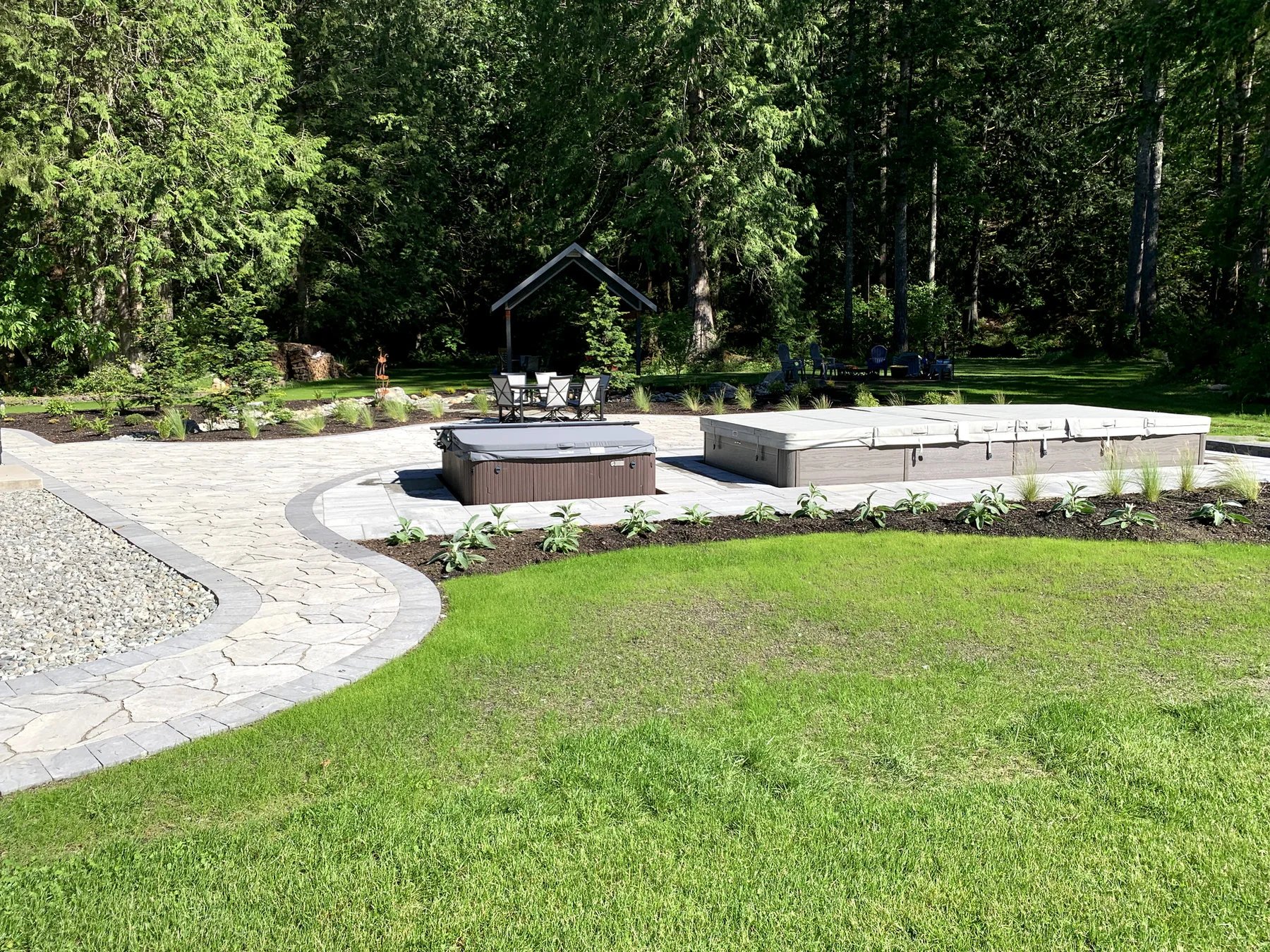 The swim spa and gathering area sit within a curved stone patio.