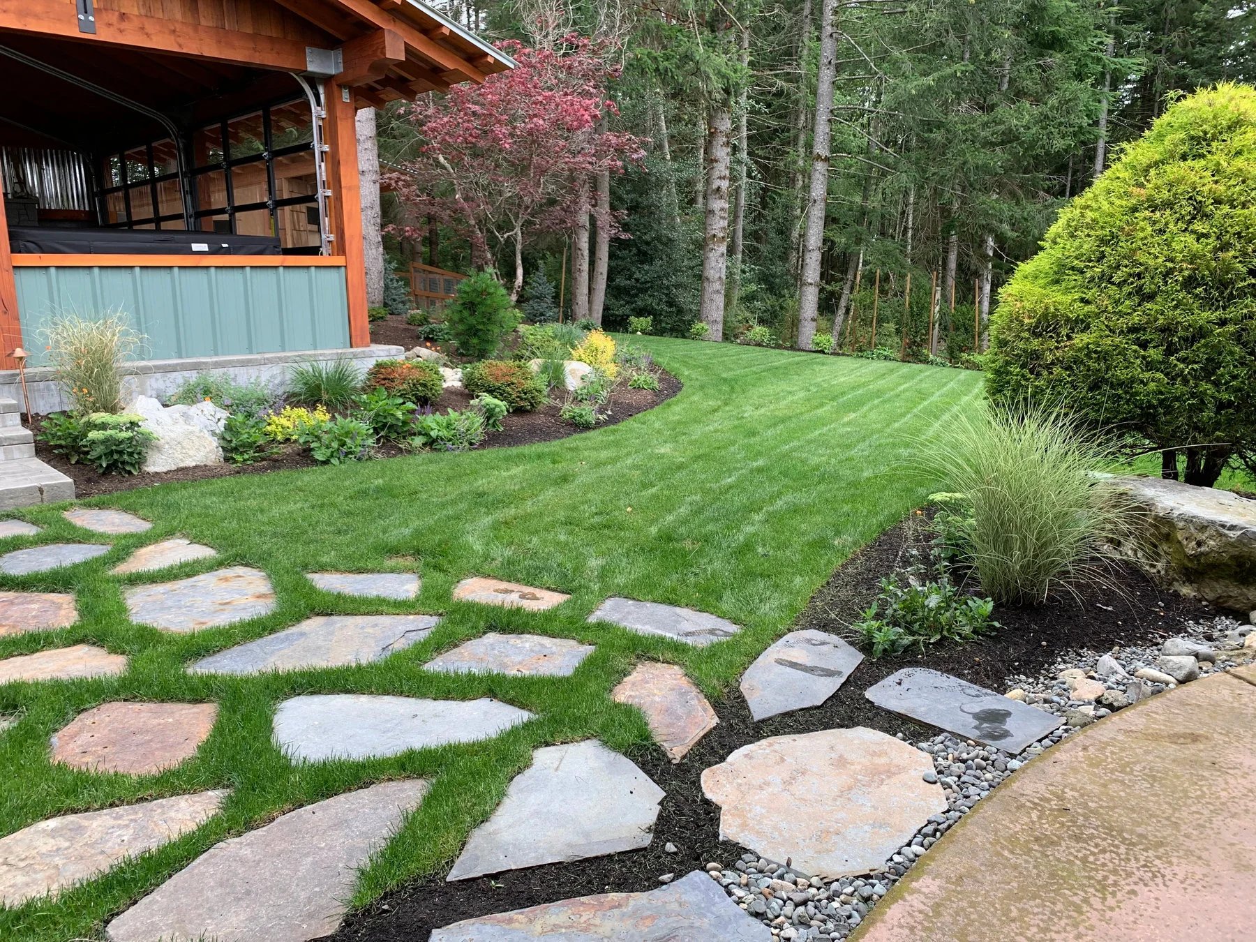 A natural stone path meets the planting beds beside the house.