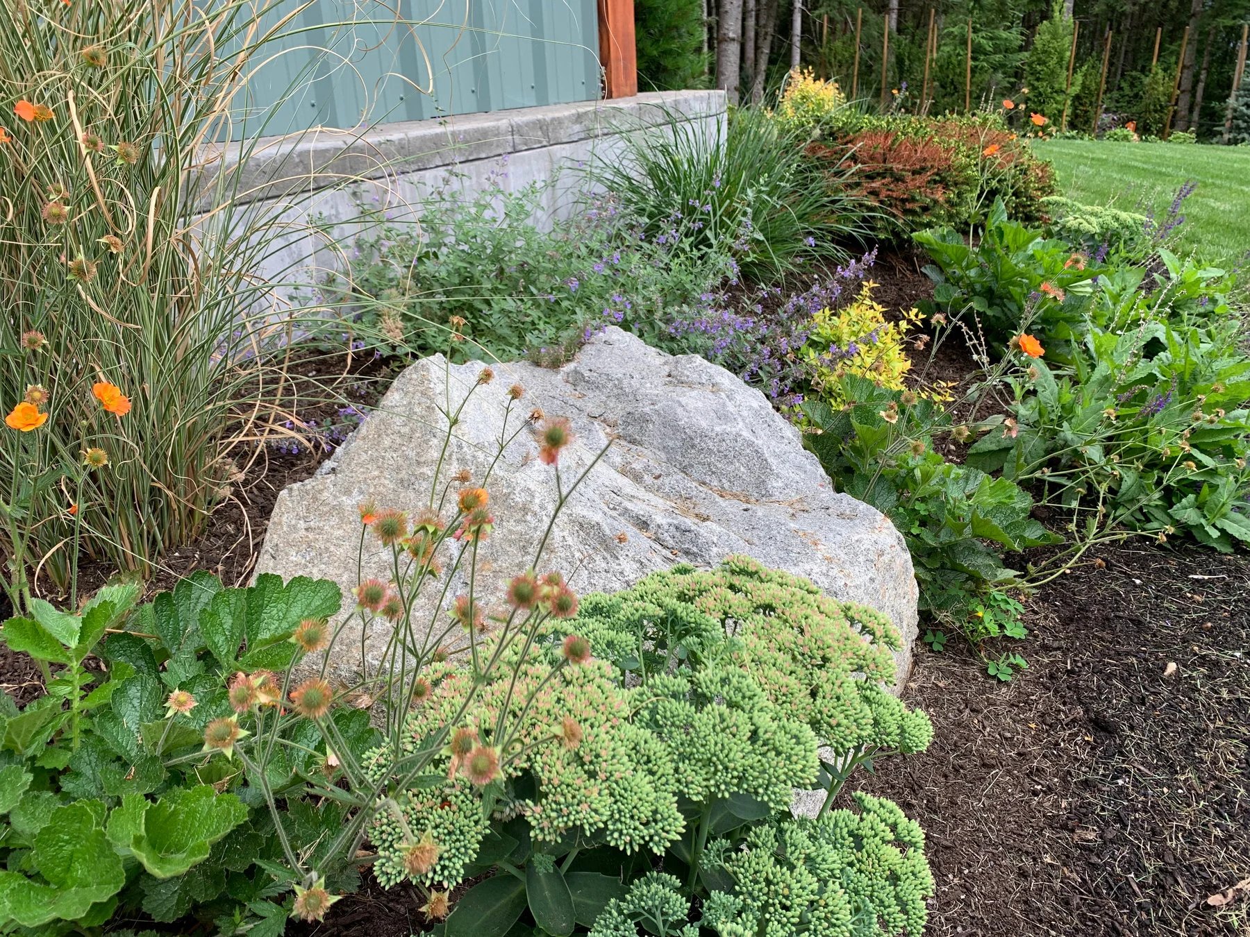 Stone, grasses, and low planting bring texture to a garden bed.