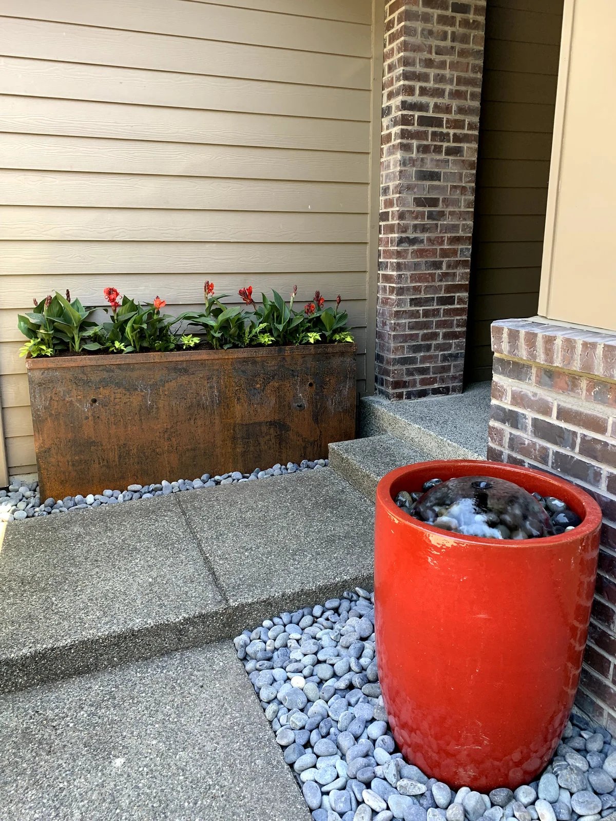 Warm Corten steel and a red container define a planted entry.